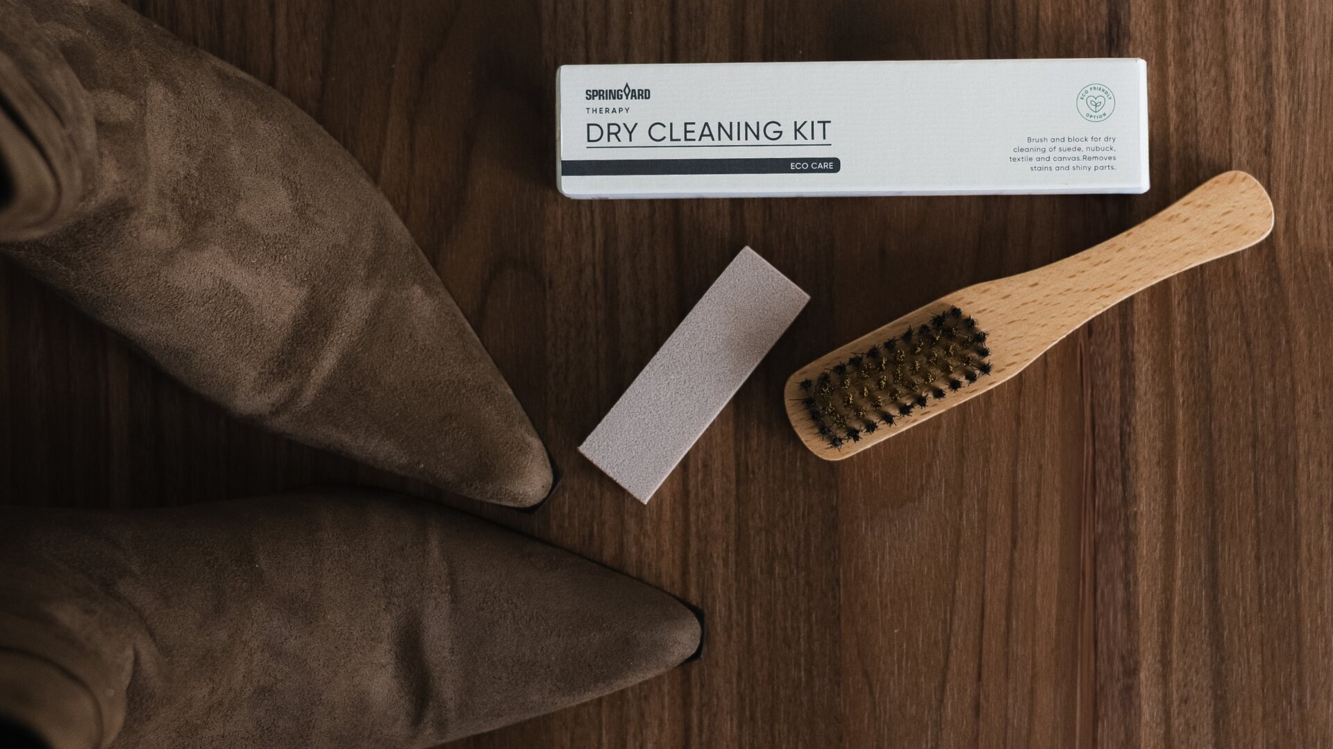 Springyard Dry Cleaning Kit med borste och rengöringsblock för skonsam rengöring av mocka och nubuck, placerat på ett träbord tillsammans med ett par mockaskor.