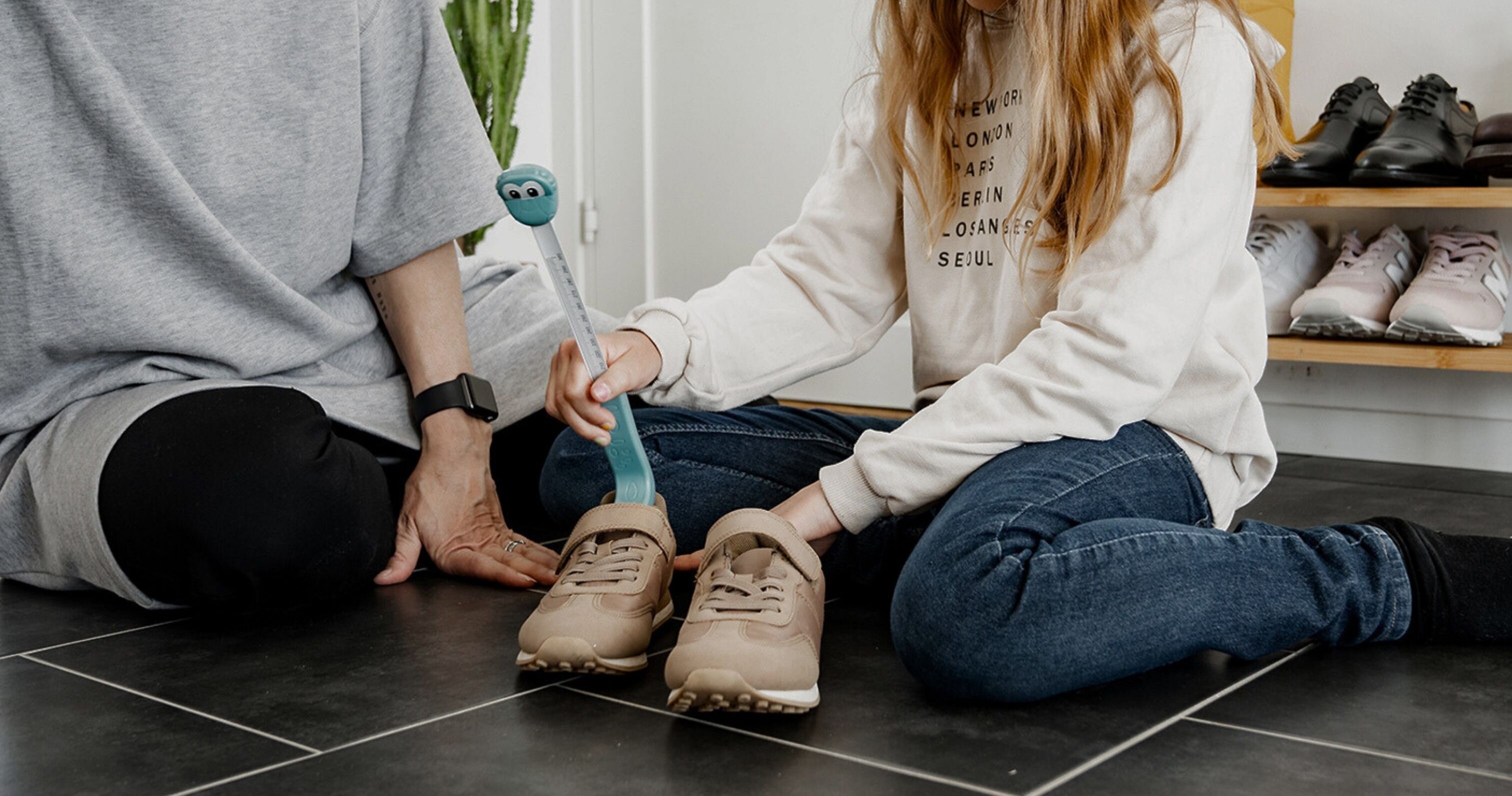Mor och dotter använder mätstickan Kiddy för att mäta skostorlek